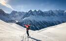 Personne de dos descendant une piste en snowboard les bras en l'air